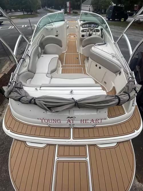 White boat with tan deck and cushioned seating on a trailer, viewed from the stern.