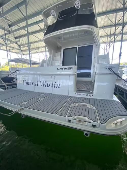 White yacht docked indoors with gray deck and green water reflection, named “Kings Makin”
