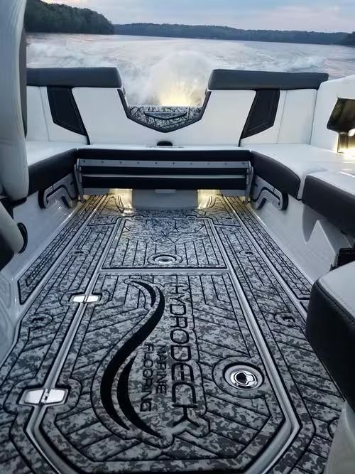 Boat cabin seating with black-and-white carpet, facing a calm lake at sunset