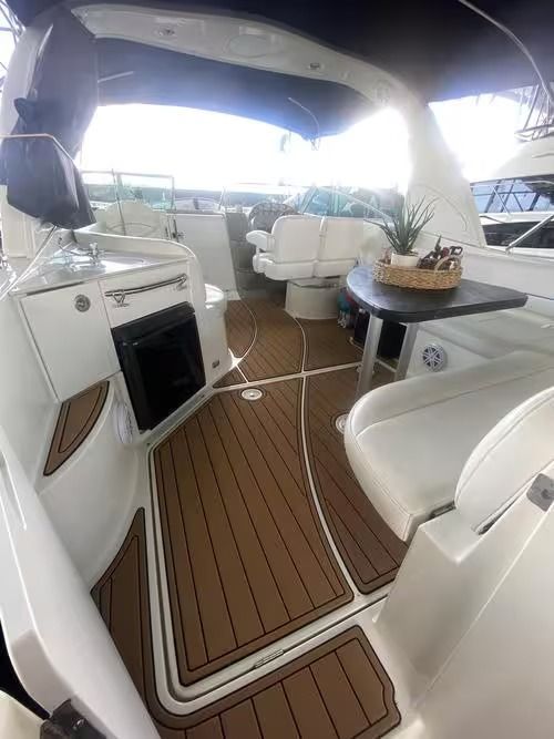 Boat cabin with white seating, wood decking, and a small table under a canopy