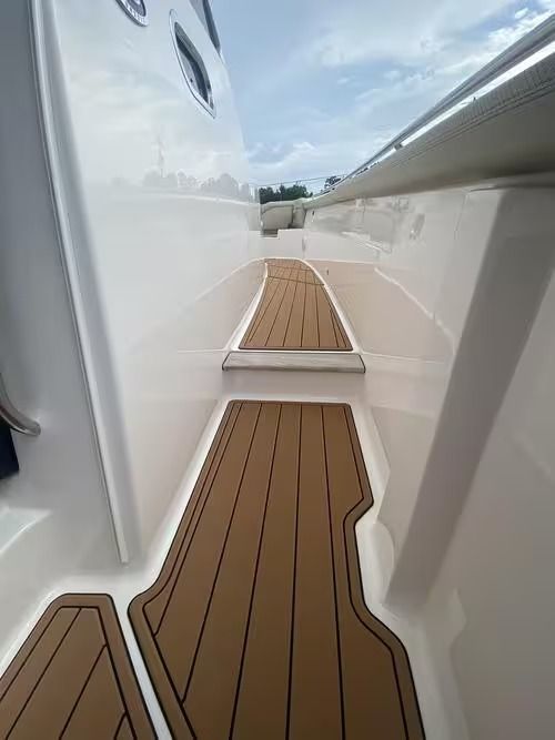 Narrow boat deck with teak flooring and white sides, viewed from the stern toward the bow