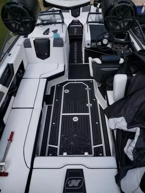 Boat cockpit with white and black seating, center walkway, and twin steering wheels, viewed from aft.