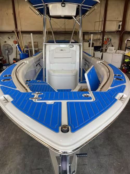 Blue-and-white fishing boat in a workshop, seen from the bow.