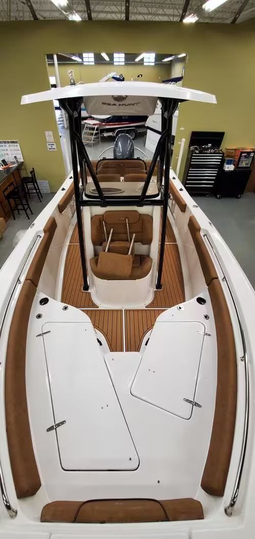 White boat interior with wood deck and a center console under construction in a workshop.