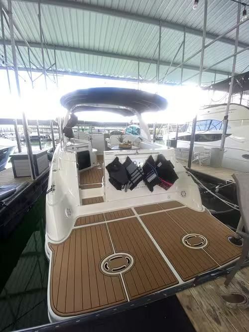 White yacht cockpit with tan deck, black cushions, and twin hatches in a covered marina slip