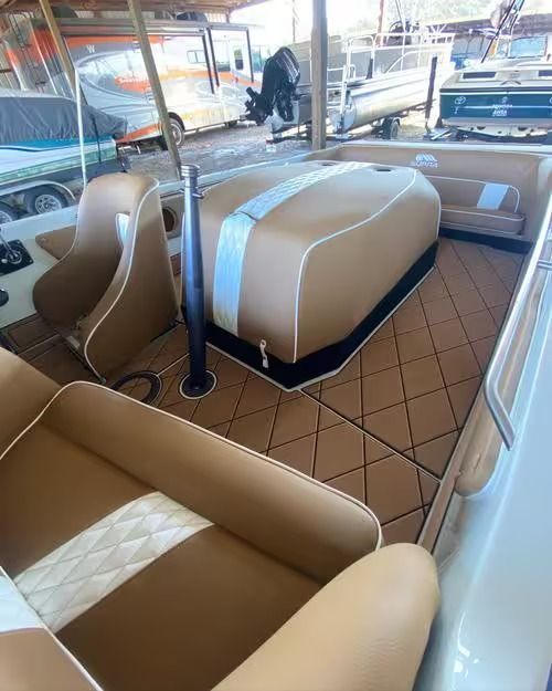 Tan leather boat interior with quilted seating, tan floor, and a central covered console.