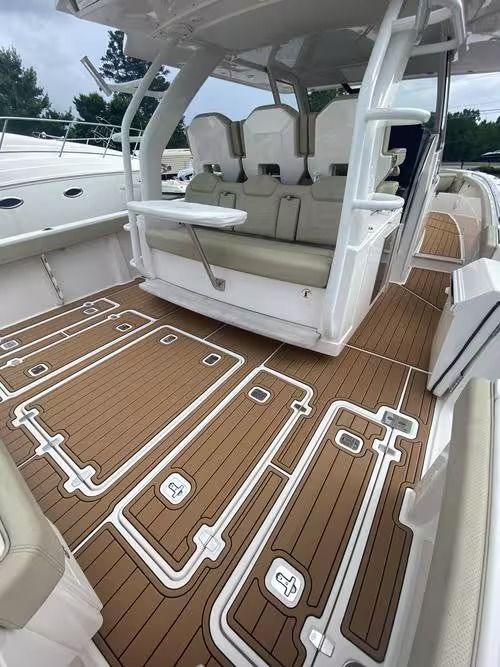Luxury boat deck with tan non-slip flooring, white seating, and open cockpit seating area