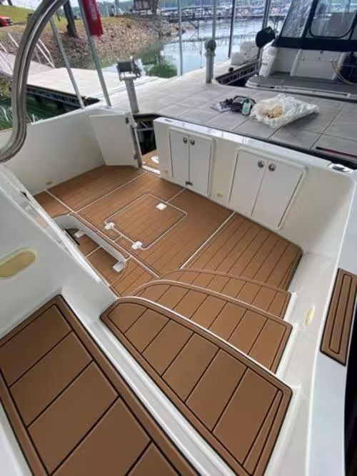 Sailboat cockpit with teak deck, white cabinets, and marina view.