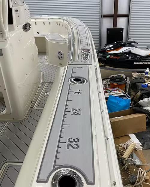 Boat deck with a gray measuring strip marked 16, 24, and 32 beside a white railing.