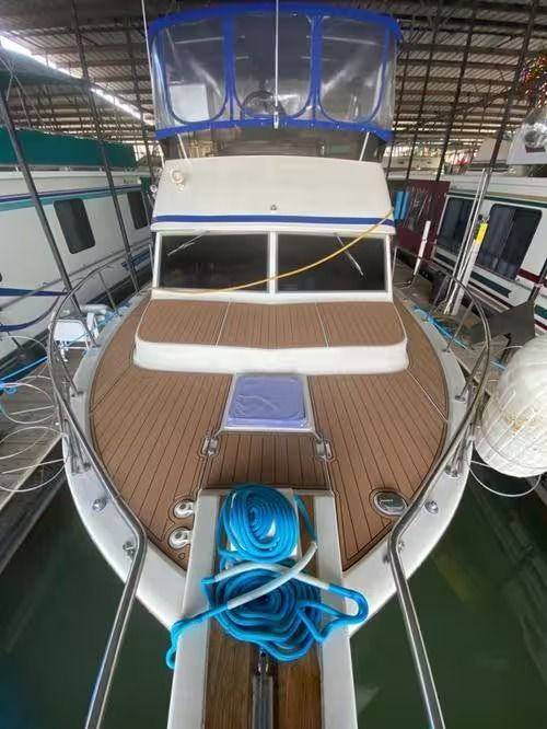 Yacht bow deck with blue bow canopy, teak flooring, and coiled blue rope in a marina.