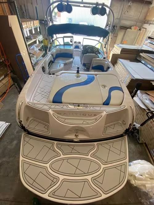 Boat in a garage with blue racing stripes and the swim platform lowered.