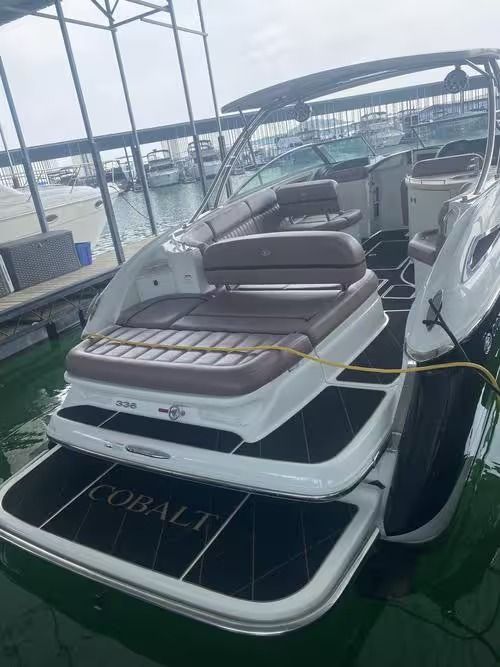 Luxury motorboat docked in a marina, with tan seats and black-and-white hull.