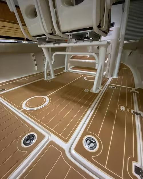 Boat deck with tan non-slip flooring, white rails, and mounted seats overhead.
