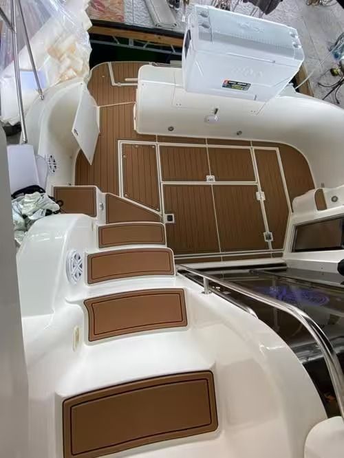 Top-down view of a yacht deck with brown cushioned seating and a central table, beside the water.