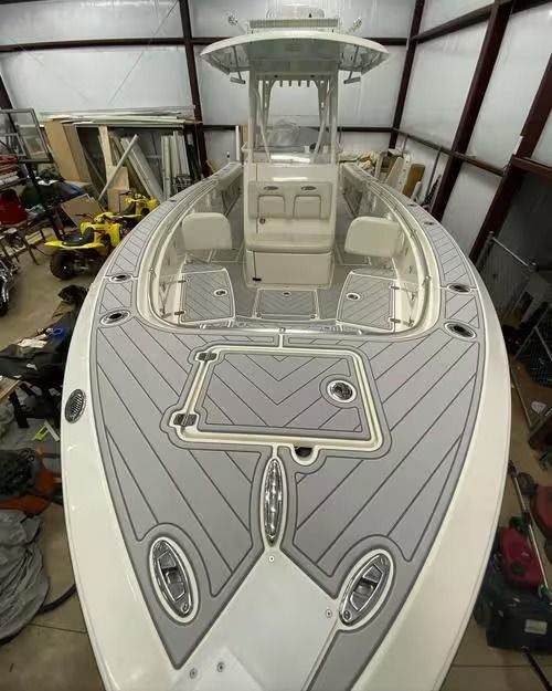 White center-console boat deck with gray non-slip flooring and a T-top in a workshop garage.