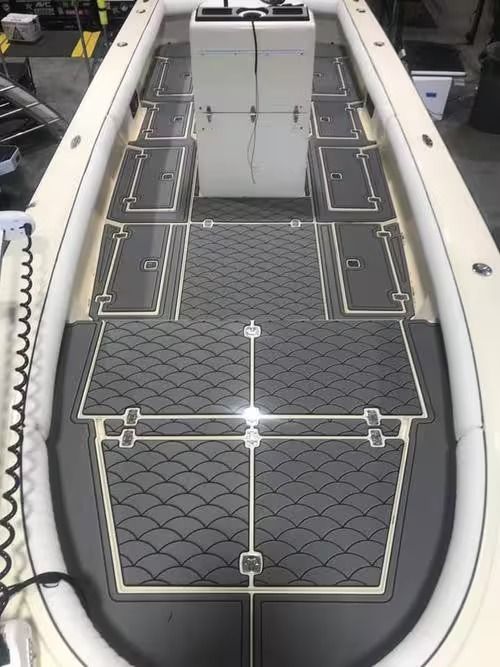 Top-down view of a small boat deck with gray patterned flooring and storage hatches.