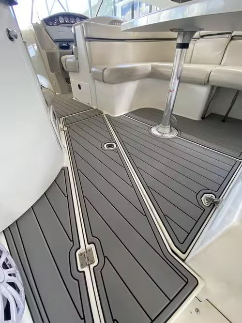 Interior of a boat cabin with gray decking, beige seating, and stainless supports