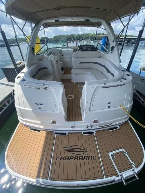 Chaparral boat cockpit and stern seating with tan teak decking under a canopy, docked on calm water