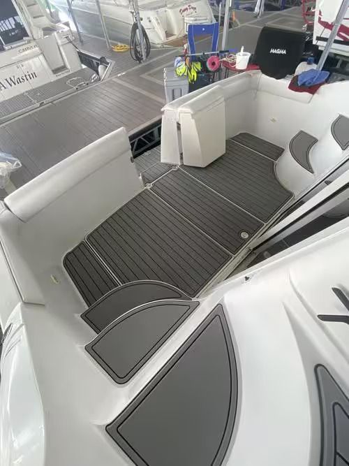 White boat cockpit with gray seating, striped floor mats, and marina background