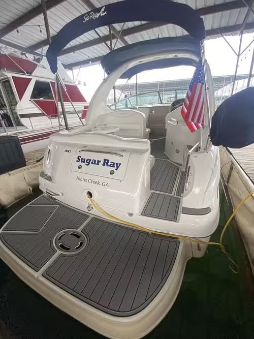 Sugar Ray boat in a marina, white deck with blue bimini top and American flag