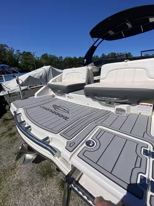 Boat deck with white cushioned seats, gray non-slip flooring, and a black canopy under a blue sky