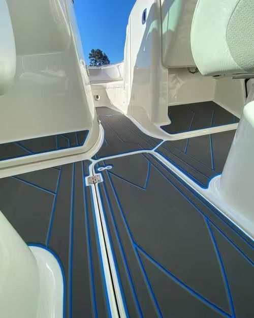 Modern boat cabin aisle with white seats and dark blue carpet, viewed toward the open deck and sky