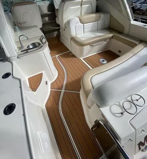 Boat cabin interior with cream seating and wood-look flooring, featuring built-in storage and cup holders.