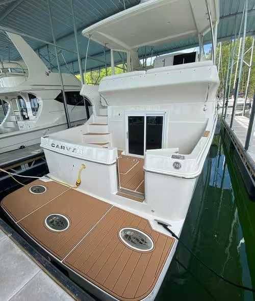 White yacht stern with tan teak deck docked in a covered marina berth