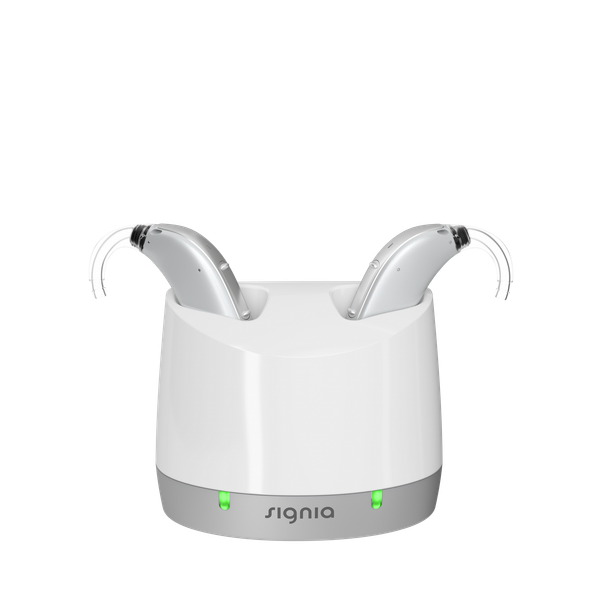 Person holding a beige hearing aid, indoors.