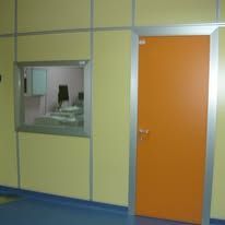 Una porta scorrevole bianca con cartello di avvertimento in un corridoio, accanto a una parete con pavimento effetto marmo.