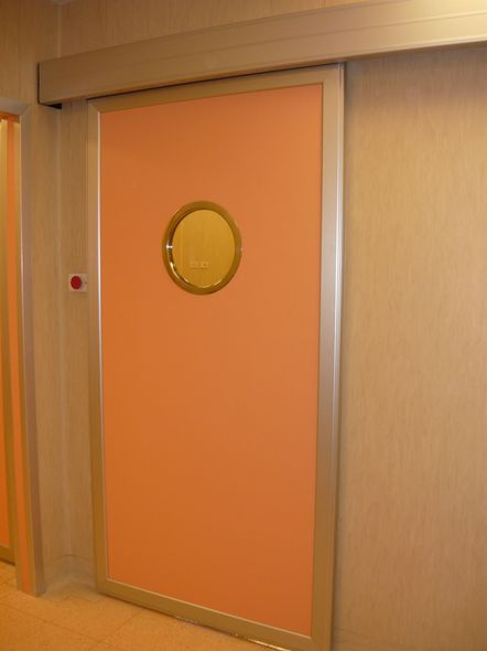 Un uomo seduto a una scrivania dietro una grande finestra in un ufficio con pareti grigie.