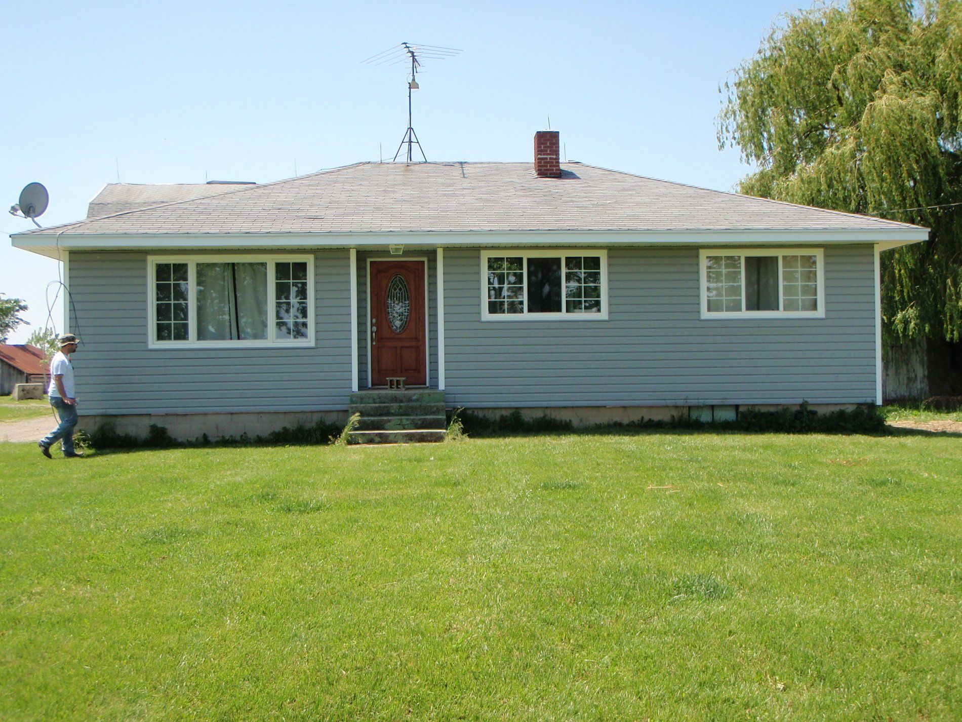 A man walking in front of a house with a red door