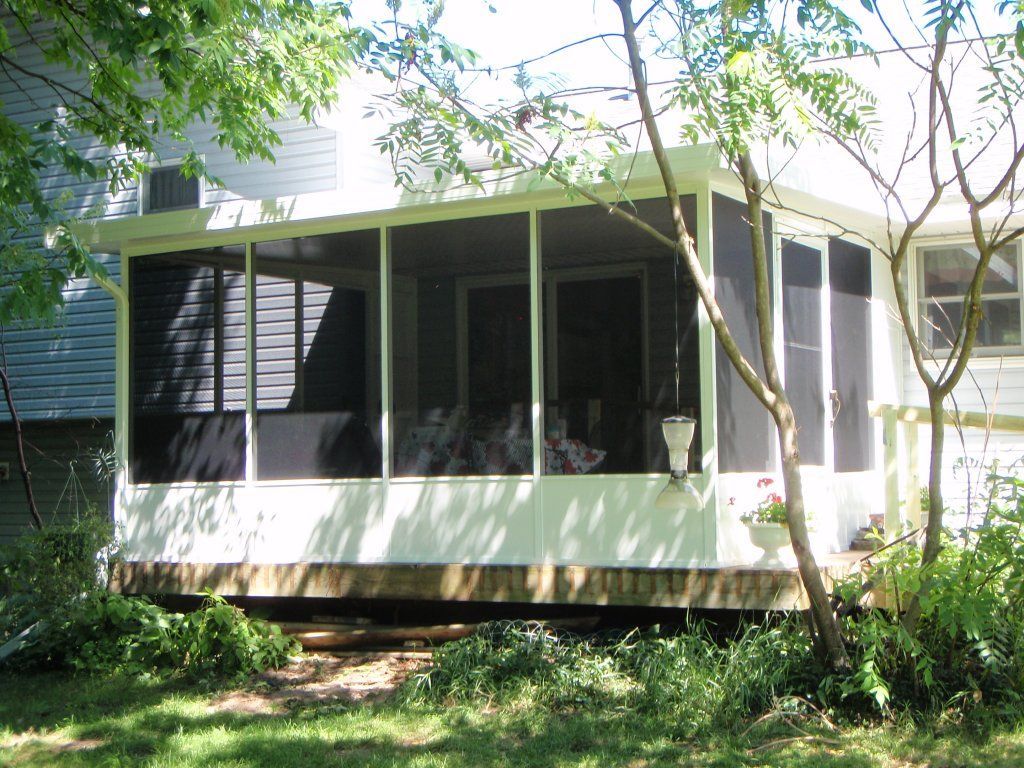A screened in porch in the backyard of a house