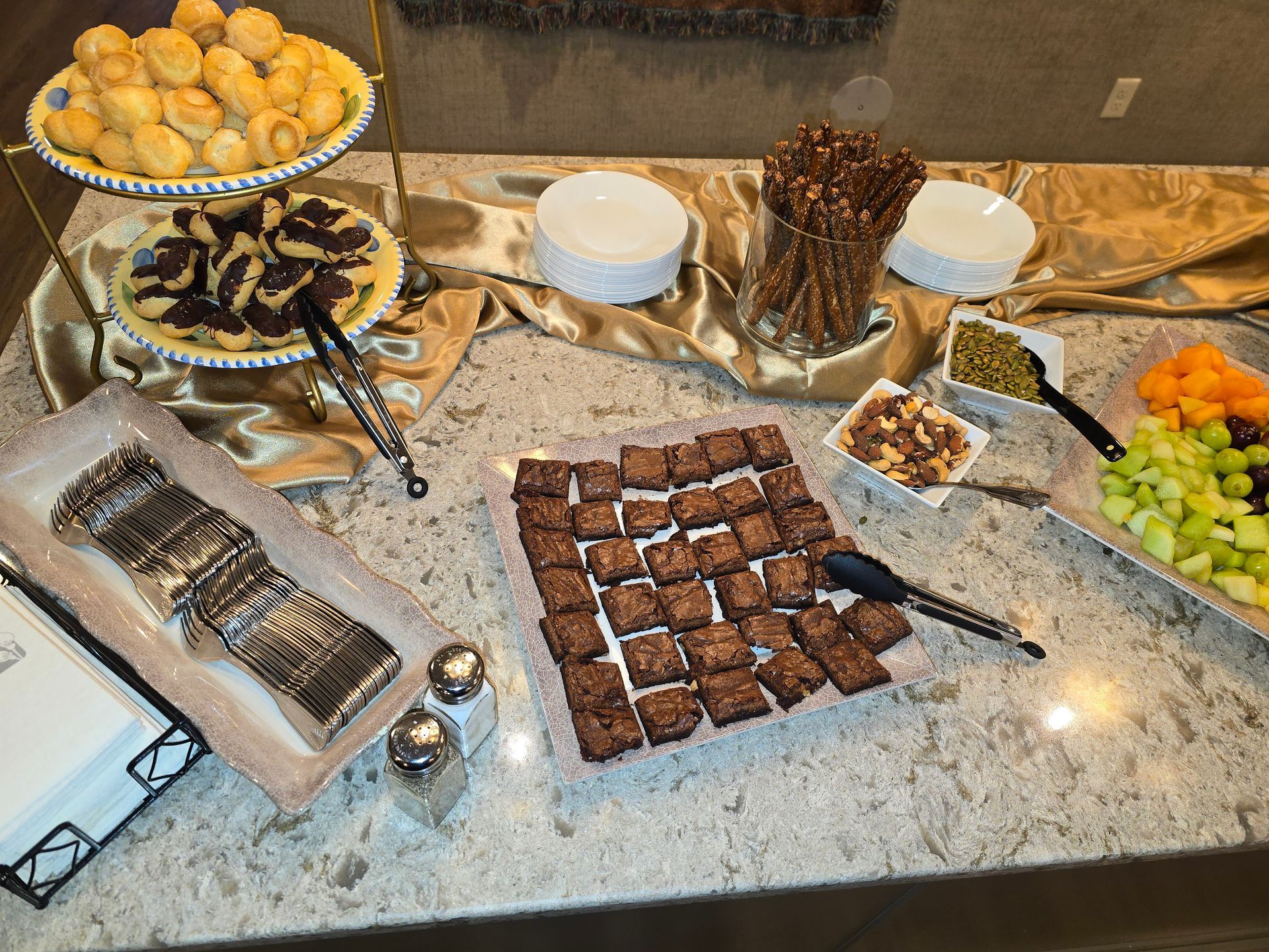 Dessert buffet with assorted pastries, brownies, fruit, and cookies on a granite countertop