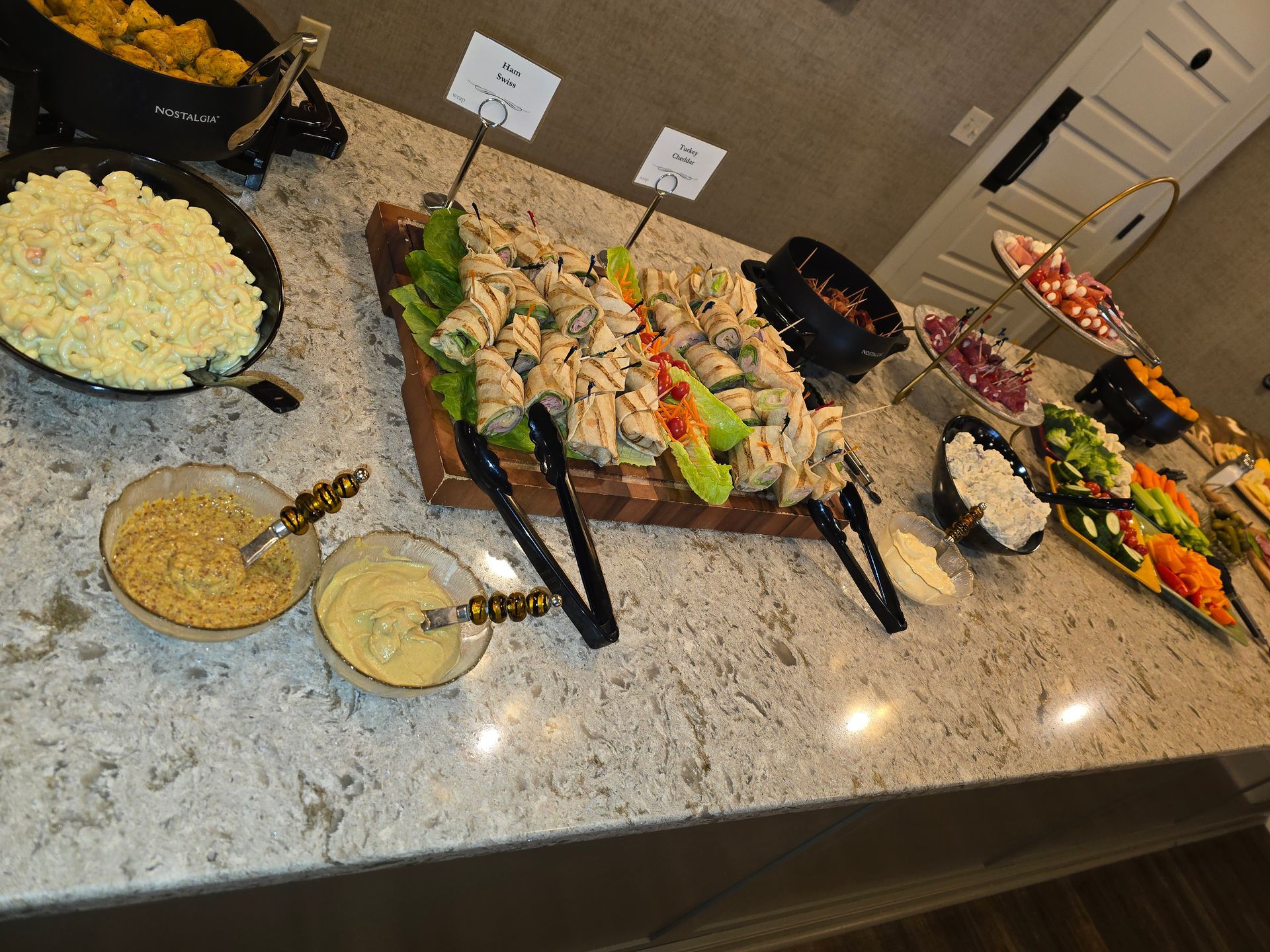 Buffet spread with salads, meats, and vegetables on a kitchen island countertop