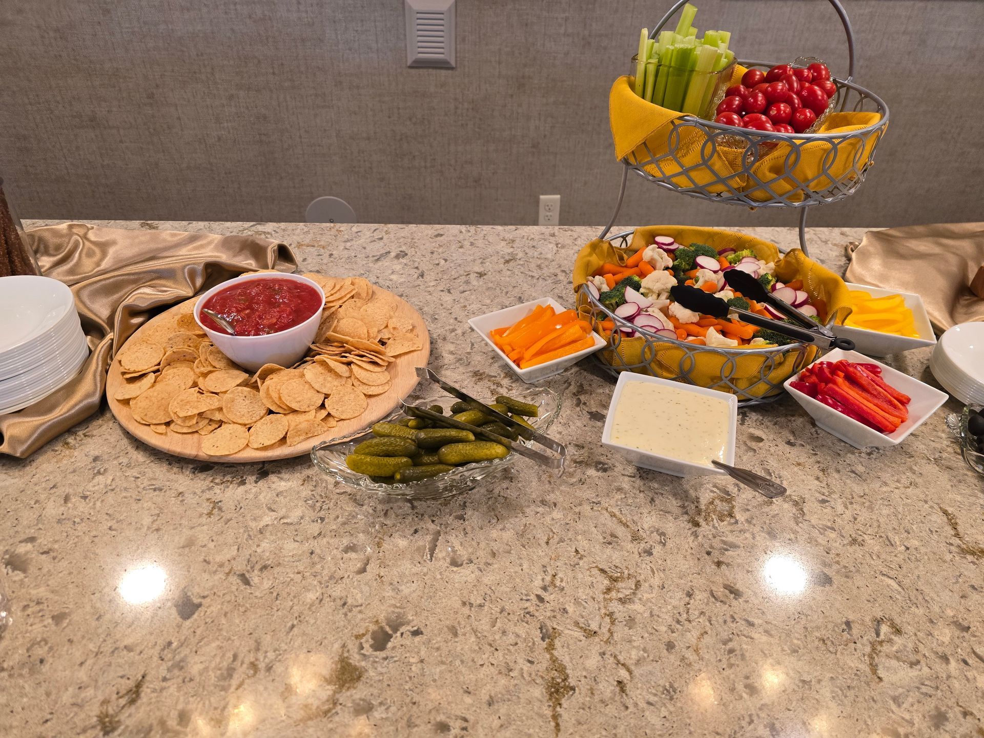 Party snack spread on a countertop with crackers, dip, veggies, fruit, and cheese trays