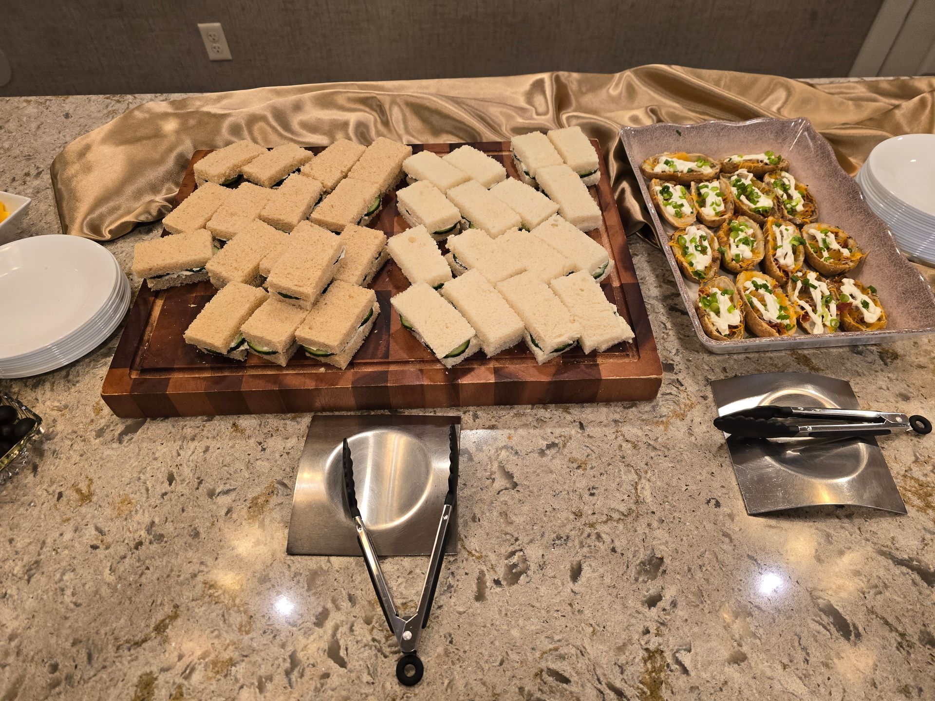 Tray of assorted finger sandwiches and cucumber bites on a countertop buffet display