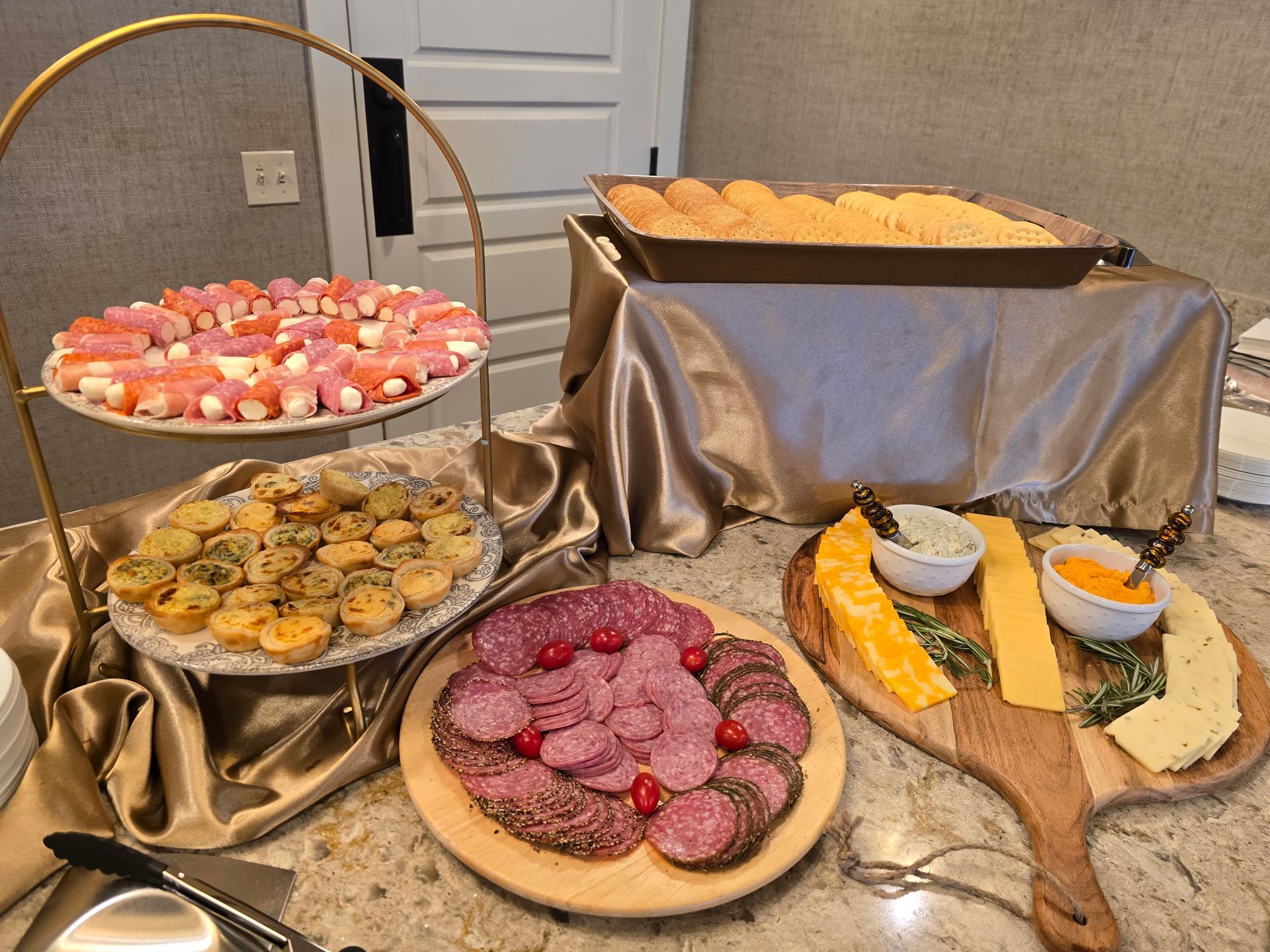 Dessert buffet with assorted pastries and fruit tarts on a gold tablecloth at an indoor event table