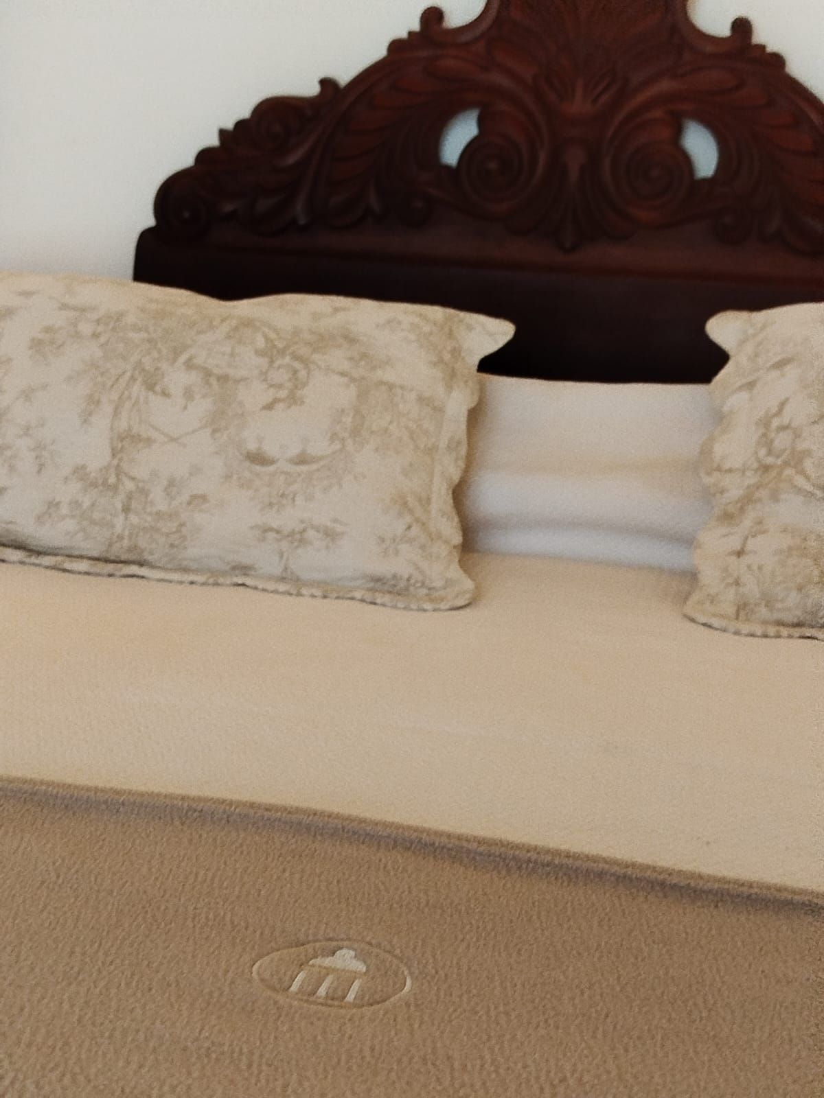 Bed with carved wooden headboard and decorative pillows.