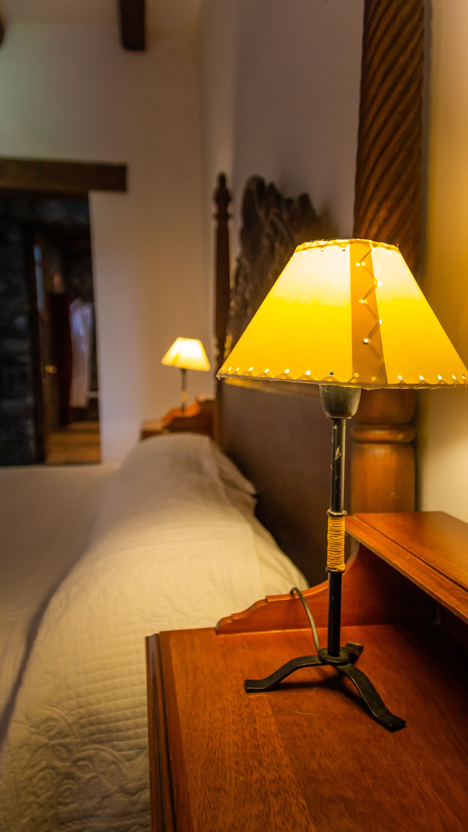 A lamp is sitting on a nightstand next to a bed.