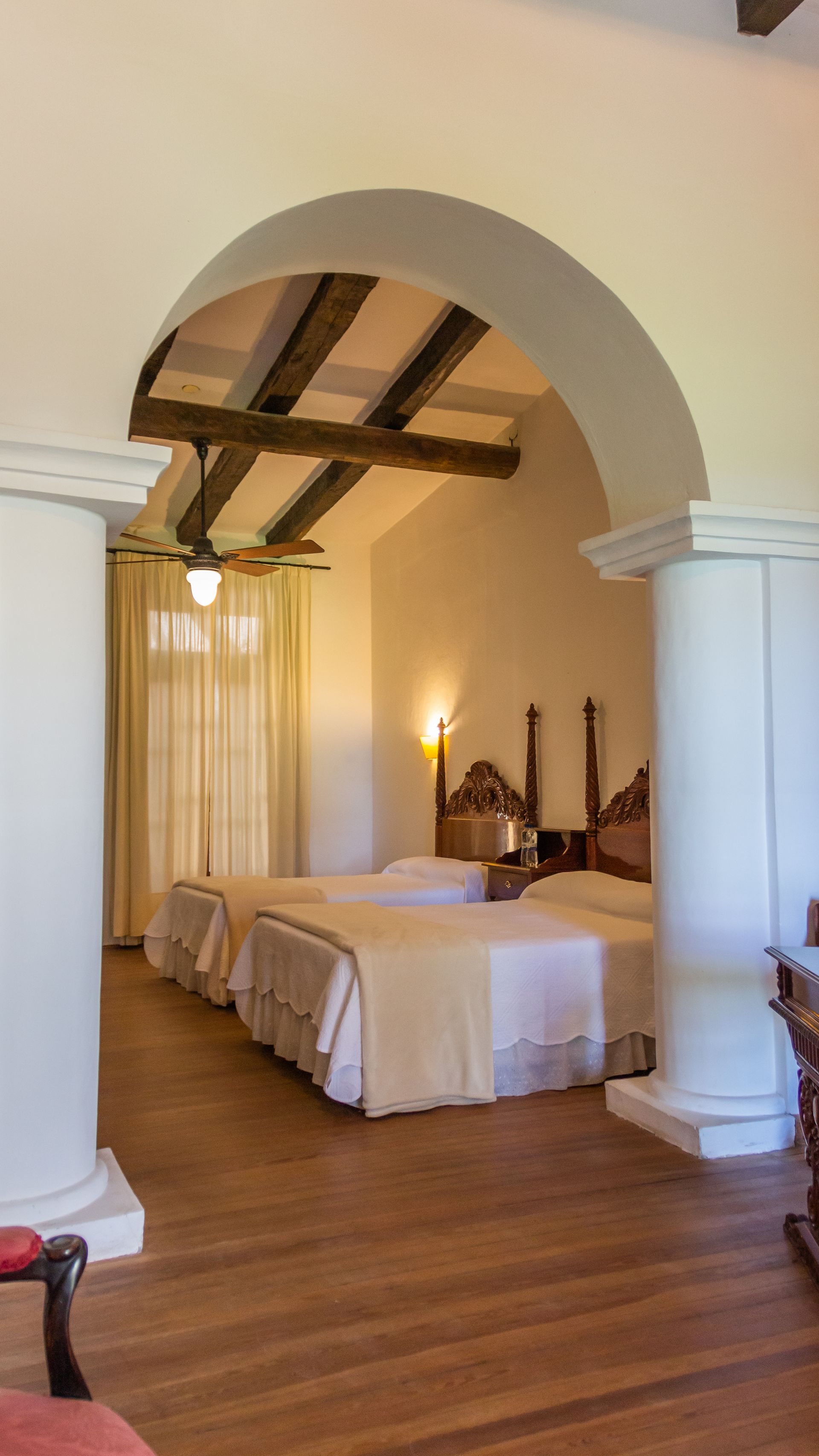 A hotel room with two beds and a wooden floor.