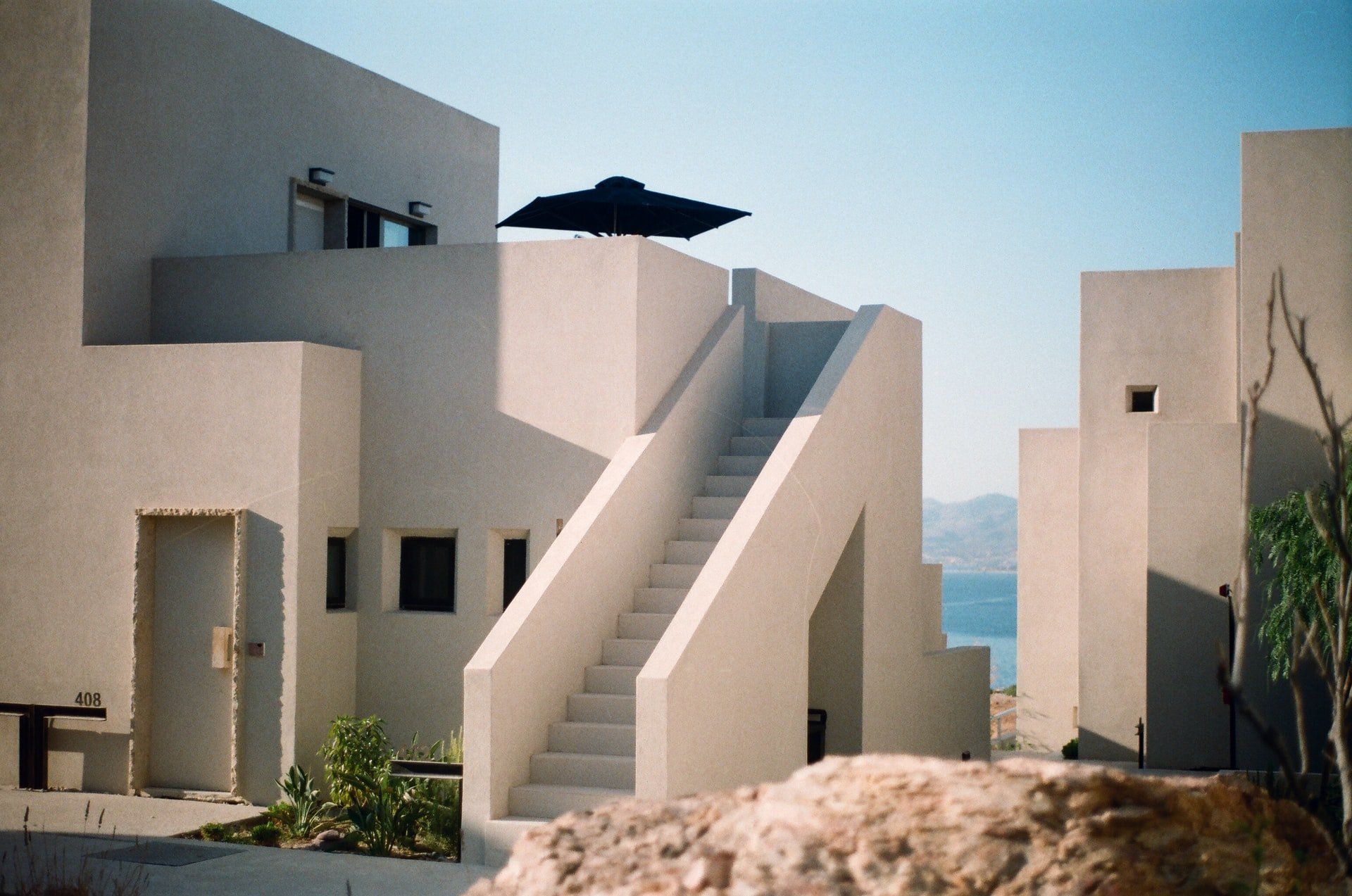 A white building with stairs and a black umbrella