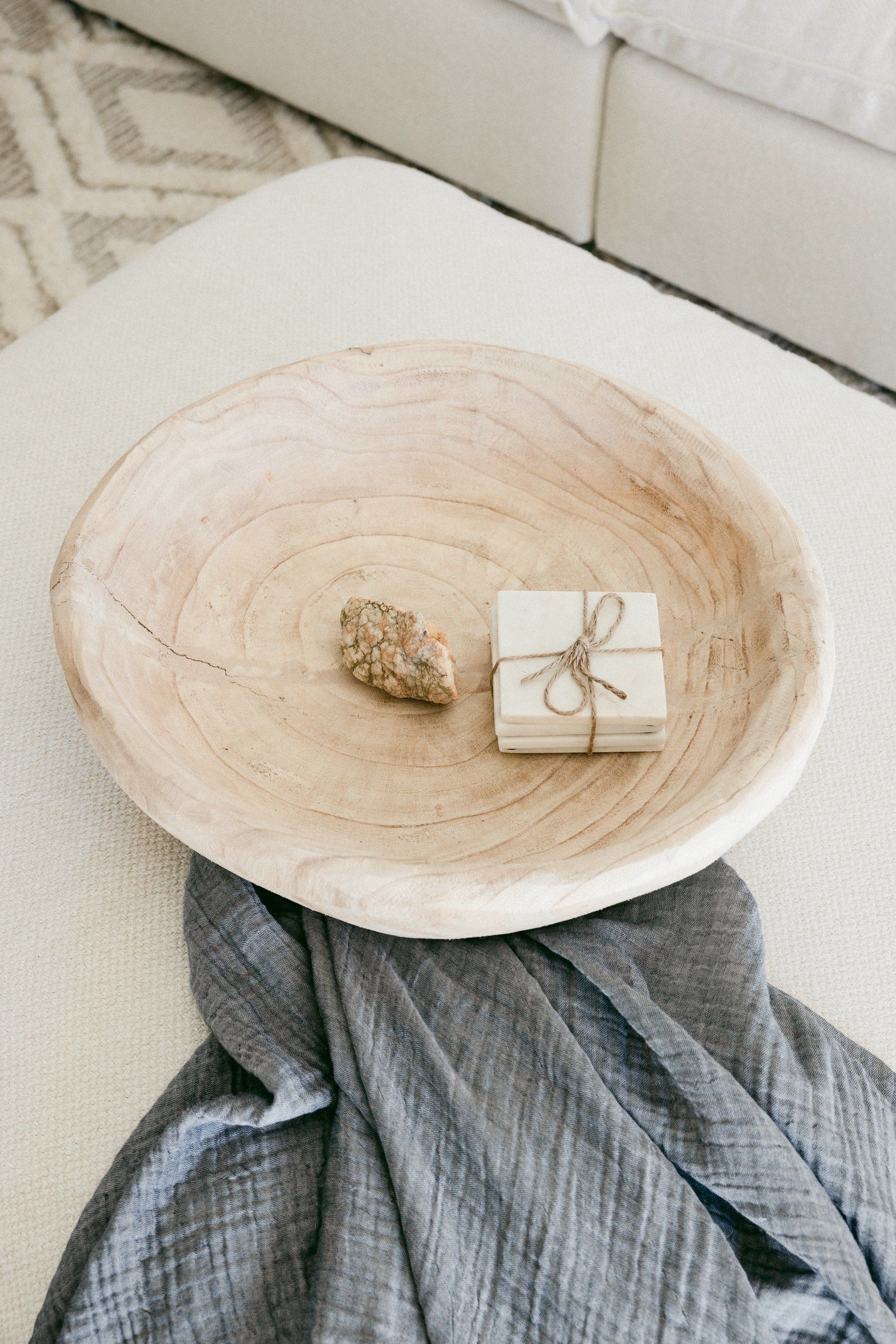 A wooden bowl sitting on top of a blanket on a table.