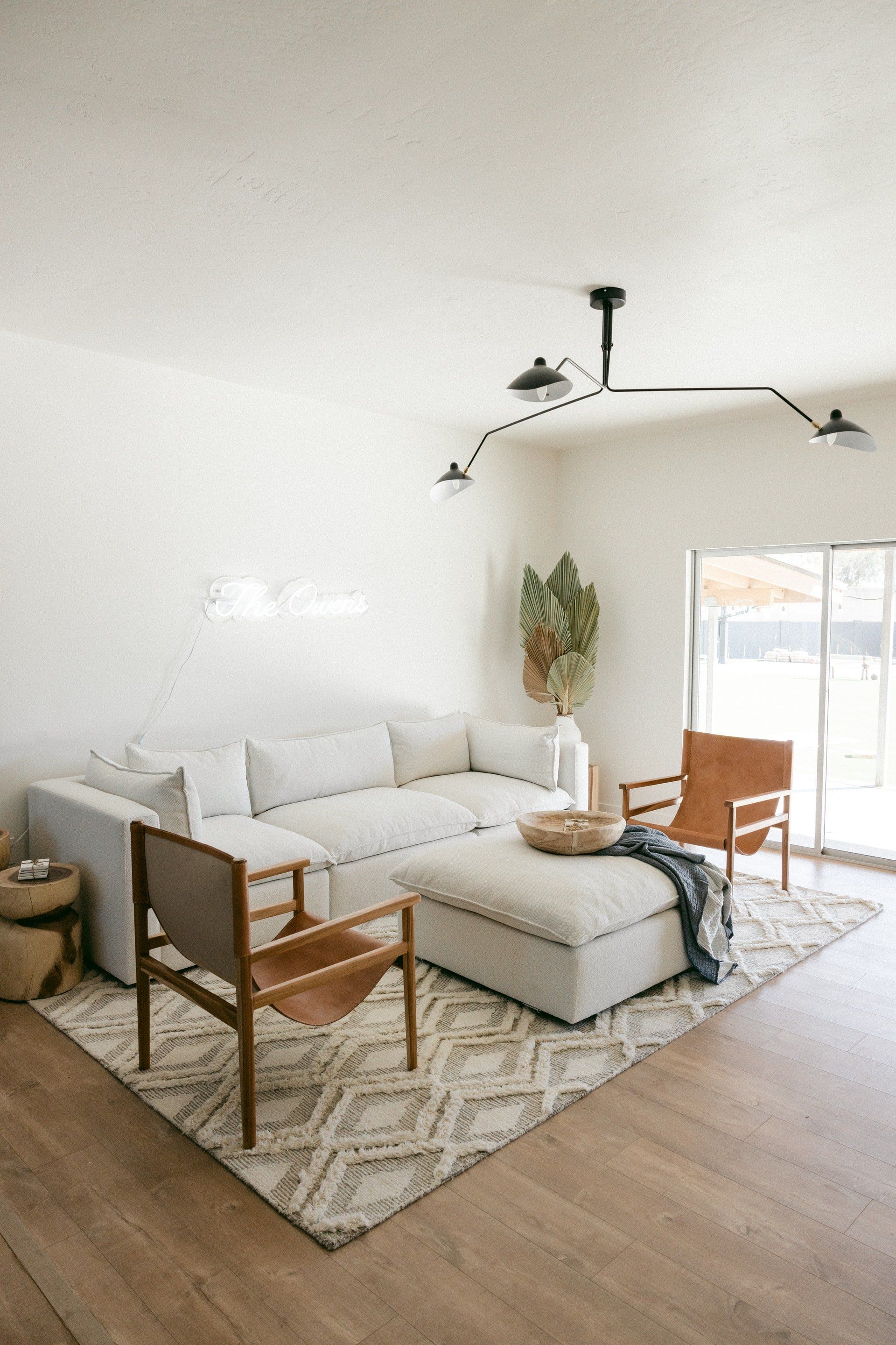A living room with a couch , chairs , ottoman and rug.