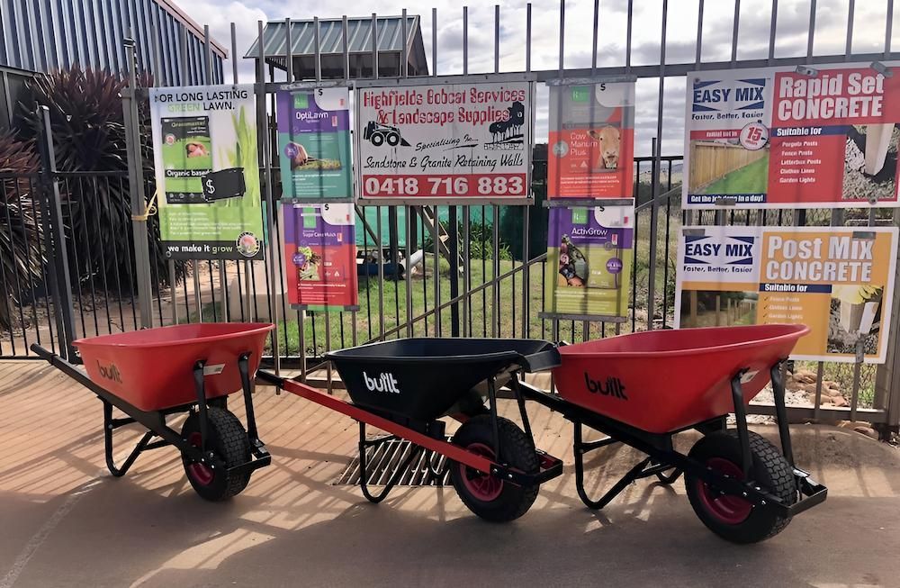 Three Wheelbarrows Are Parked in Front of a Fence — Highfields Landscape Supplies In Gatton, QLD