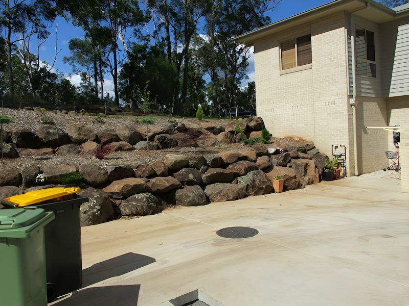 A House With a Large Rock Wall in Front of It — Highfields Landscape Supplies In Toowoomba, QLD