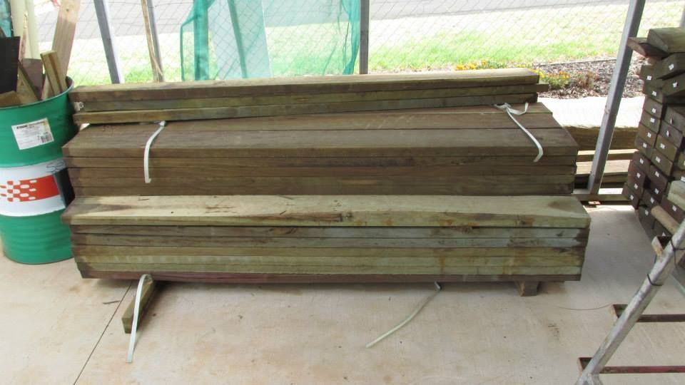 A Stack of Wood Sitting Next to a Green Barrel — Highfields Landscape Supplies In Toowoomba, QLD