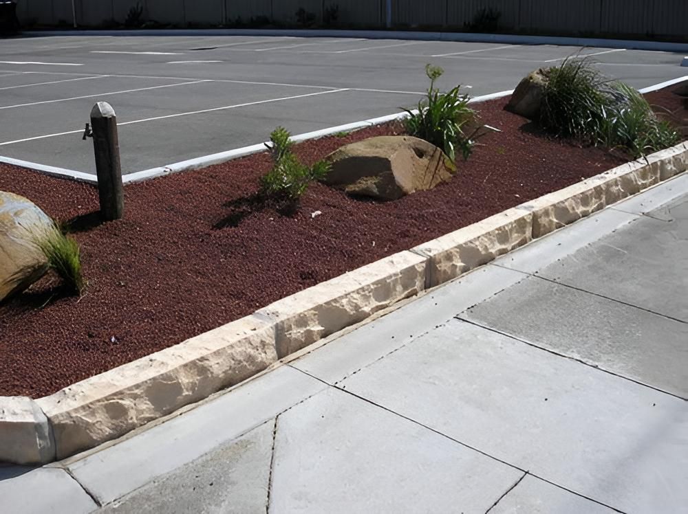 A Concrete Curb With Rocks and Plants on It — Highfields Landscape Supplies In Meringandan, QLD