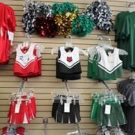 Cheerleading uniforms and matching pom-poms displayed on a store wall and rack