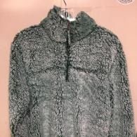 Gray fuzzy hooded jacket hanging against a pink wall